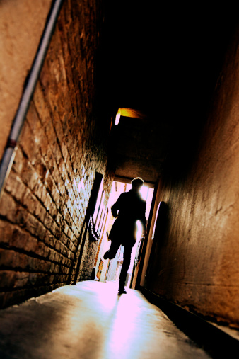 A mysterious running man silhouetted in a dark alleyway.  With cross processed film effect added in photoshop.