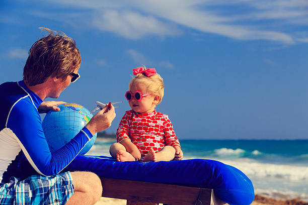 istock father and little daughter playing with globe on the beach 466184232