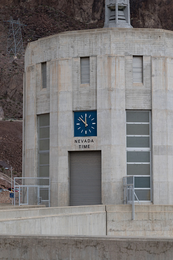This image shows Hoover Dam, a concrete arch gravity dam on the Colorado River on the border of Nevada and Arizona. This shows a clock that is on Nevada time, while there is an Arizona clock nearby.