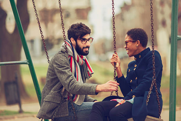 istock happy mixed race couple playing on swing 466189069