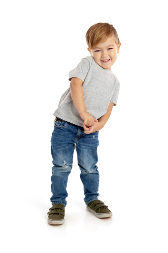 Preschool boy sitting on white background smiling.
