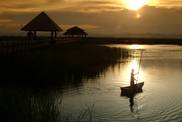 istock Thai villager punt on lake in Sunset . 466192739