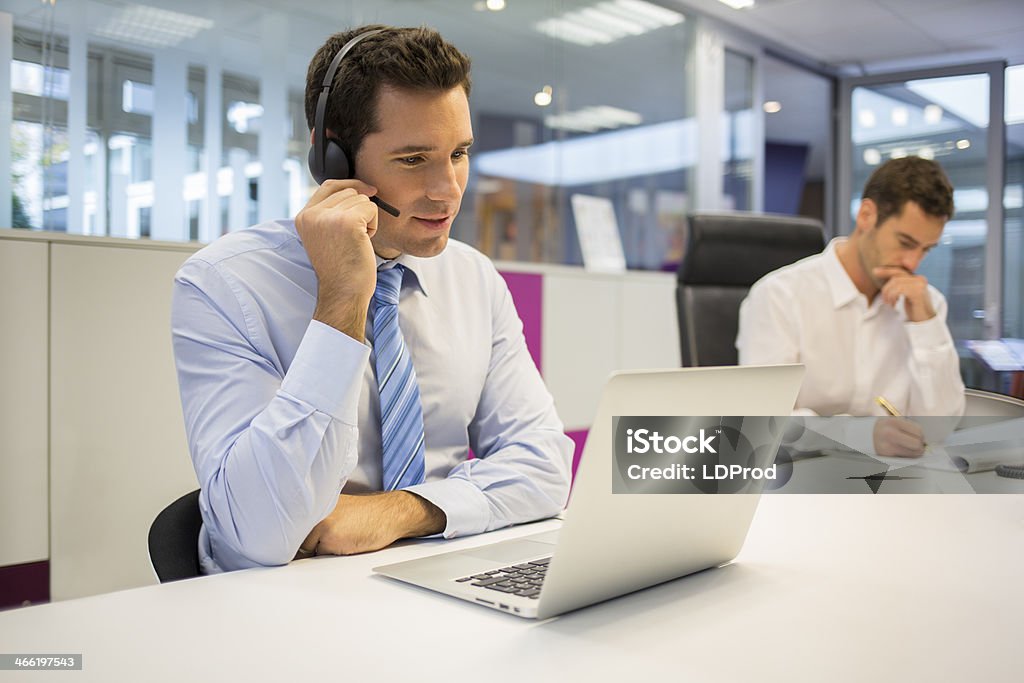 Businessman at office on the phone with headset, Skype Male business talk computer laptop Home Video Camera Stock Photo