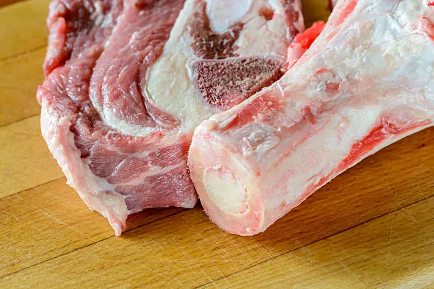 Closeup of meat of beef and marrowbone on a wooden cutting board, will be boil for the preparation of broth