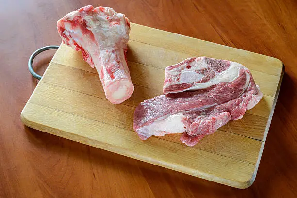 Meat of beef and marrowbone on a wooden cutting board, will be boil for the preparation of broth