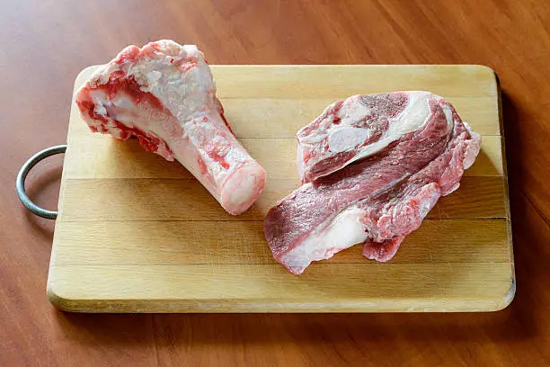 Meat of beef and marrowbone on a wooden cutting board, will be boil for the preparation of broth