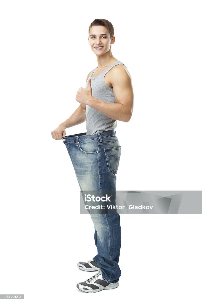 Man showing how much weight he lost A handsome young man showing how much weight he lost whis thumb up isolated on white background Abdomen Stock Photo