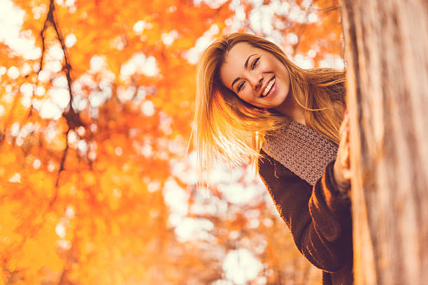 istock Happy woman peeking behind the tree in the park. 466201638