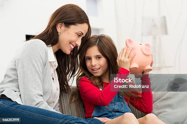 Mother Looking At Daughter Holding Piggybank Stock Photo - Download Image Now - Child, Piggy Bank, Giving
