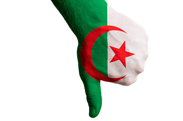 Hand with thumb down gesture in colored algeria national flag as symbol of negative political, cultural, social management of country