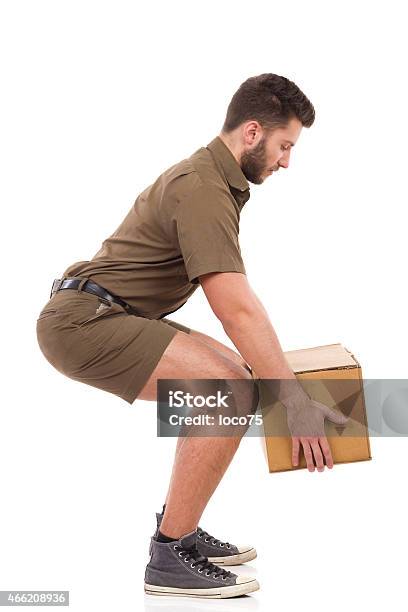 Courier Picking Up A Package Stock Photo - Download Image Now - Picking Up, Men, Squatting Position