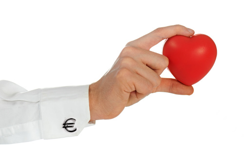 Businessman with Euro cufflinks is holding a heart-shaped object.