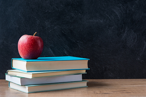 istock Apple on stacked books in front of a blackboard at school 466211630