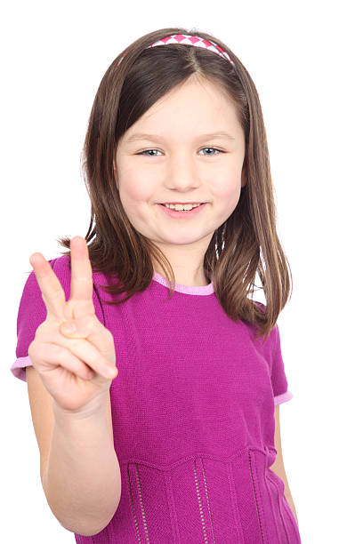 joven chica sonriente en un vestido morado dar la señal de la paz. - peace sign counting child human finger fotografías e imágenes de stock