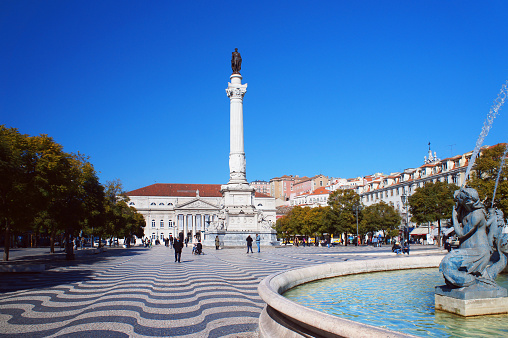 Lisbon, Portugal - February 9, 2015: People walk at the Rossio Square near Column of Pedro IV in the sunny afternoon in Lisbon, Portugal.
