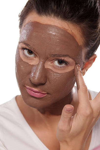 Young woman enjoys applying face mask stock photo