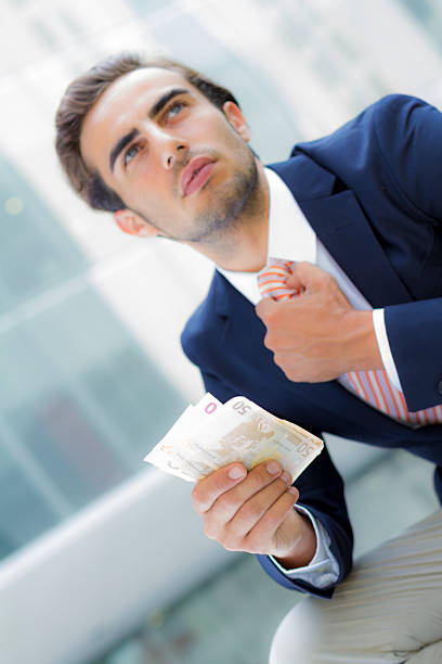 istock Young businessman outside office holding banknotes 466217147
