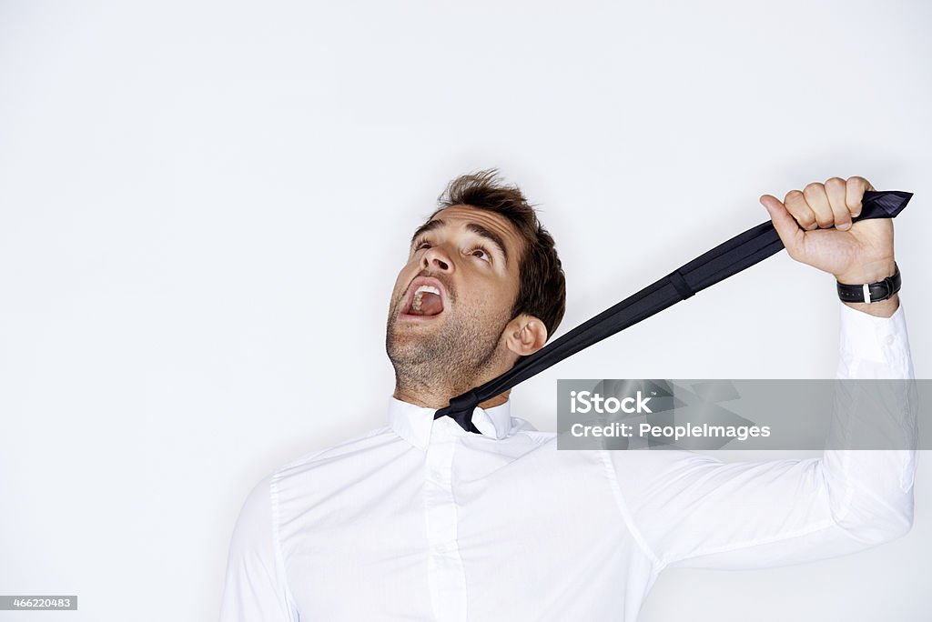 Strangled by formality Handsome young guy yelling while being strangling himself with his neck tie Necktie Stock Photo