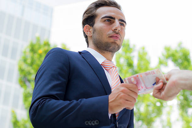 Young businessman outside office taking banknotes