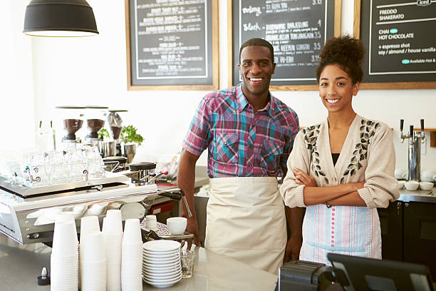 istock Smiling coffee shop owner with employee 466221345