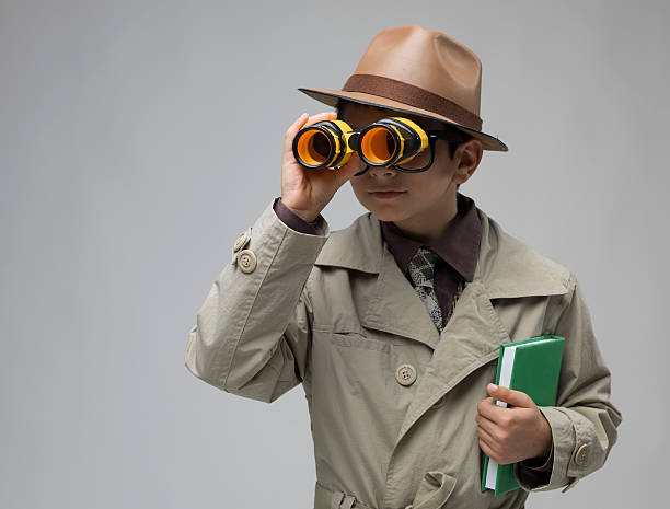 istock Little detective looking through hand held telescope on gray background 466223673