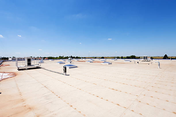 Roof of an industrial building under clear blue skies Flat roof with skylight and hydro insulation membranes cladding construction equipment photos stock pictures, royalty-free photos & images