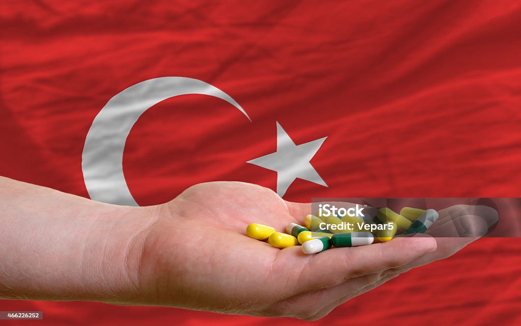 holding pills in hand and flag of turkey man holding capsules in front of complete wavy national flag of turkey symbolizing health, medicine, cure, vitamines and healthy life 2015 Stock Photo