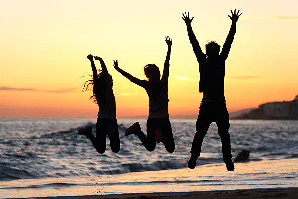 istock Friends silhouette jumping happy on the beach at sunset 466234712