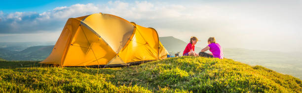 istock Children camping on idyllic summer mountain top beside tent panorama 466237718