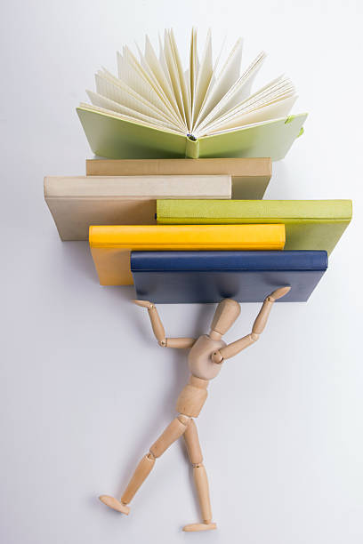 деревянный манекен имеет a куча красочные книги. - success practicing book stack стоковые фото и изображения