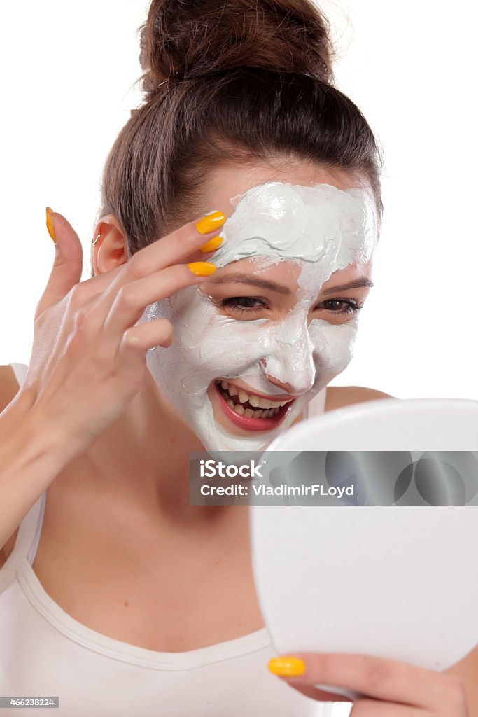 Young woman enjoys applying face mask young woman enjoys applying face mask 2015 Stock Photo