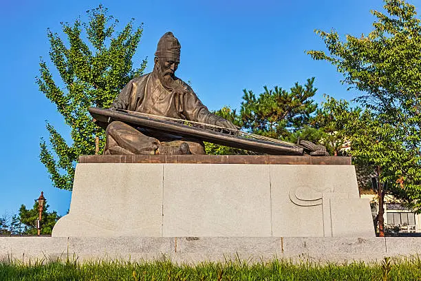 Sitting Confucius bronze statue with traditional asian musical instrument in South Korea