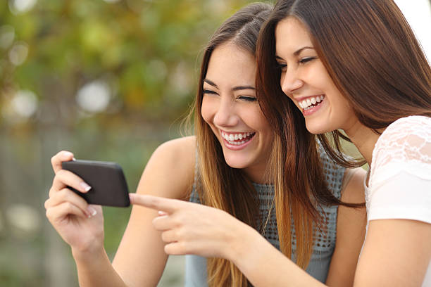 istock Funny women friends sharing media in a smart phone 466240780