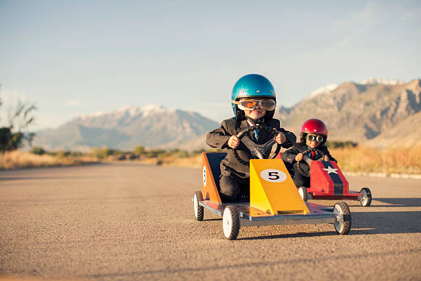 istock Young Boy Races Toy Car Wearing Business Suit 466242971