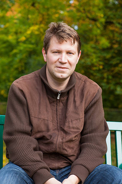 istock young man in the autumn park sitting on bench 466244593