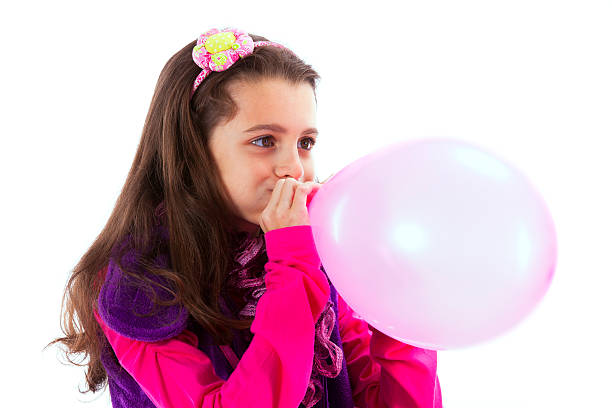 Beautiful child blowing a balloon stock photo