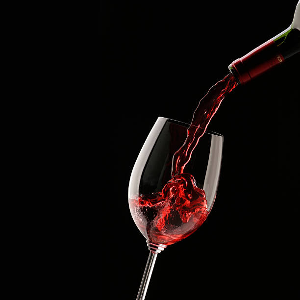 istock Pouring red wine into wine glass on a black background 466245534