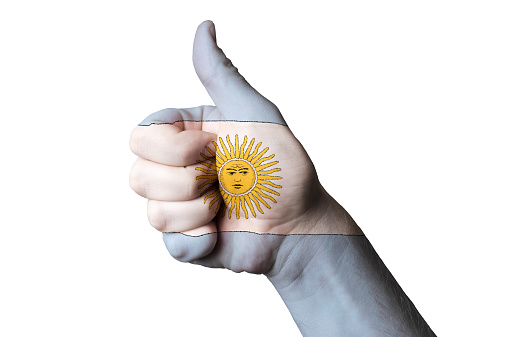 Hand with thumb up gesture in colored argentina national flag as symbol of excellence, achievement, good, - for tourism and touristic advertising, positive political, cultural, social management of country