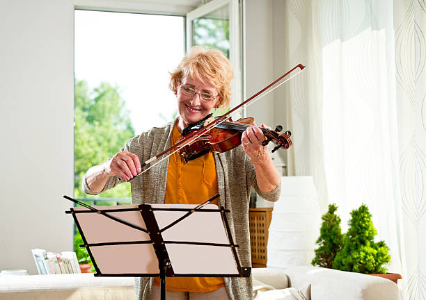 istock Senior woman playing violin at home 466246894
