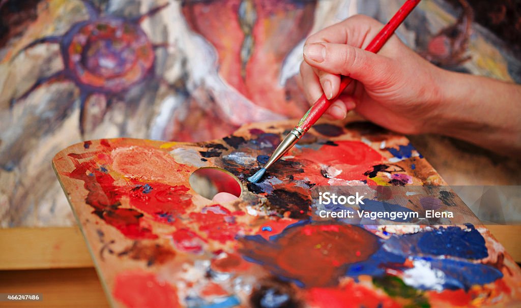 A artist using a palate with a lot of paint Artist brush mix color oil painting on palette is holding in his hand closeup Artist Stock Photo