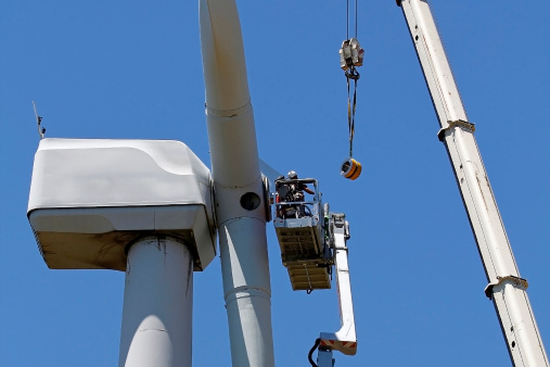 Wind turbine being repaired, assisted by crane and elevator