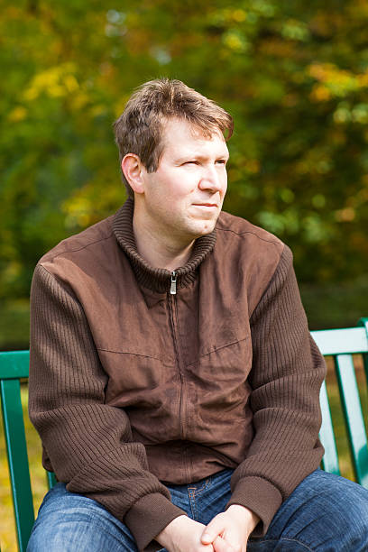 istock young man in the autumn park sitting on bench 466248431