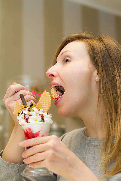 jeune femme dégustation de tasse de crème glacée avec cuillère - spoon tasting women sex symbol photos et images de collection