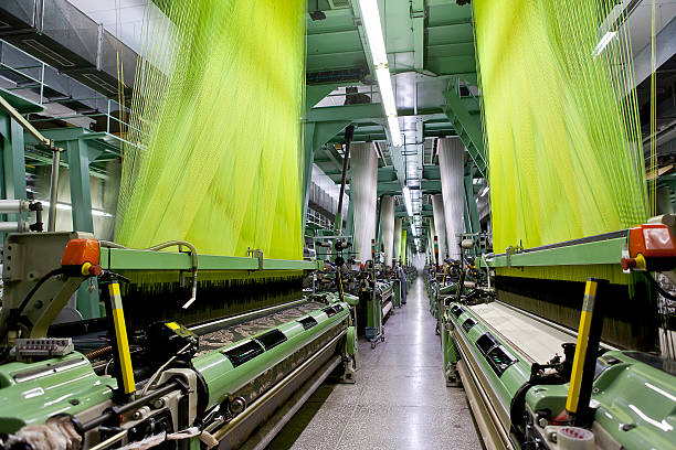 Green operating machines at a textile factory Wide angle and perspective from textile factory polyester photos stock pictures, royalty-free photos & images