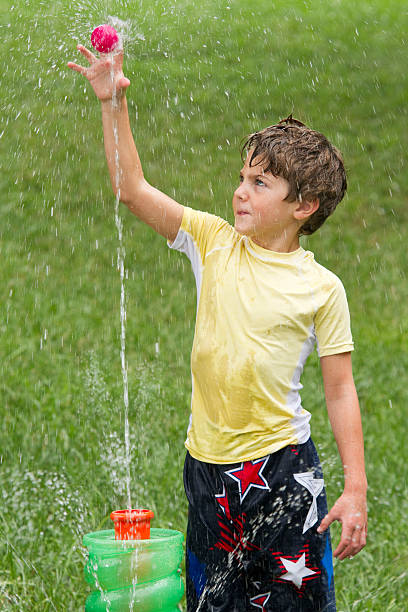 istock Boy Outside In Yard Playing With Water Fountain Toy Ball 466249931