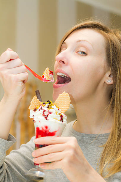 jeune femme dégustation de tasse de crème glacée avec cuillère - spoon tasting women sex symbol photos et images de collection