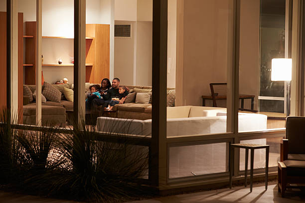 Family Watching TV At Home Viewed From Outside Mixed Race Family Watching TV At Home Viewed From Outside african american architecture stock pictures, royalty-free photos & images