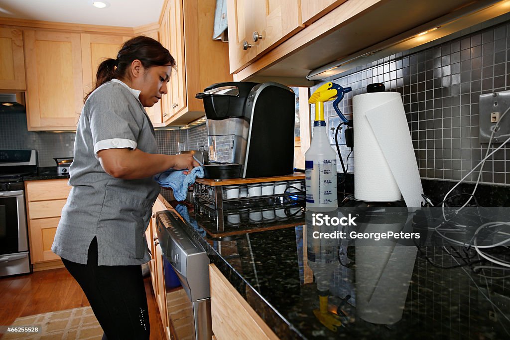 Cleaning Kitchen Spring Cleaning. Scrubbing coffee maker and kitchen counter. Domestic Staff Stock Photo