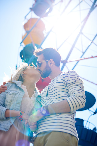 Loving couple kissing against the background of Ferris wheel