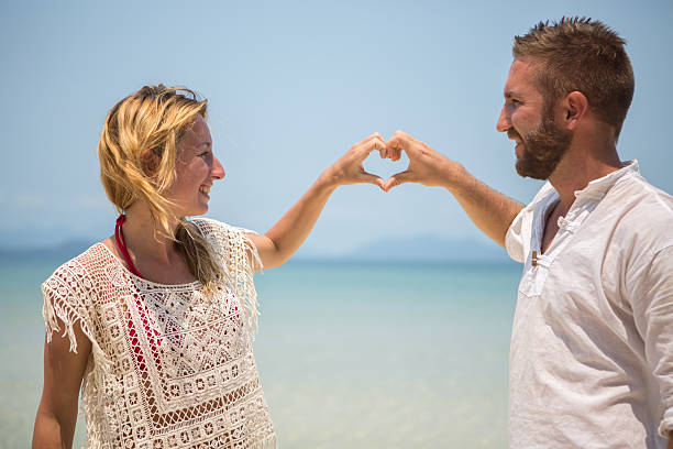 istock Loving couple on tropical beach making heart shape 466260972